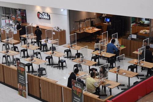 Diners at a restaurant in Bangkok eat within plastic partitions set up to maintain social distancing on Jan. 28, 2021.