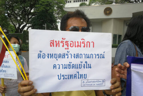 A protester holds up a sign that reads, "The U.S. must stop instigating conflicts in Thailand," during a rally in front of the U.S. embassy in Bangkok on Apr. 20, 2021. Photo: @monkey_acting / Twitter